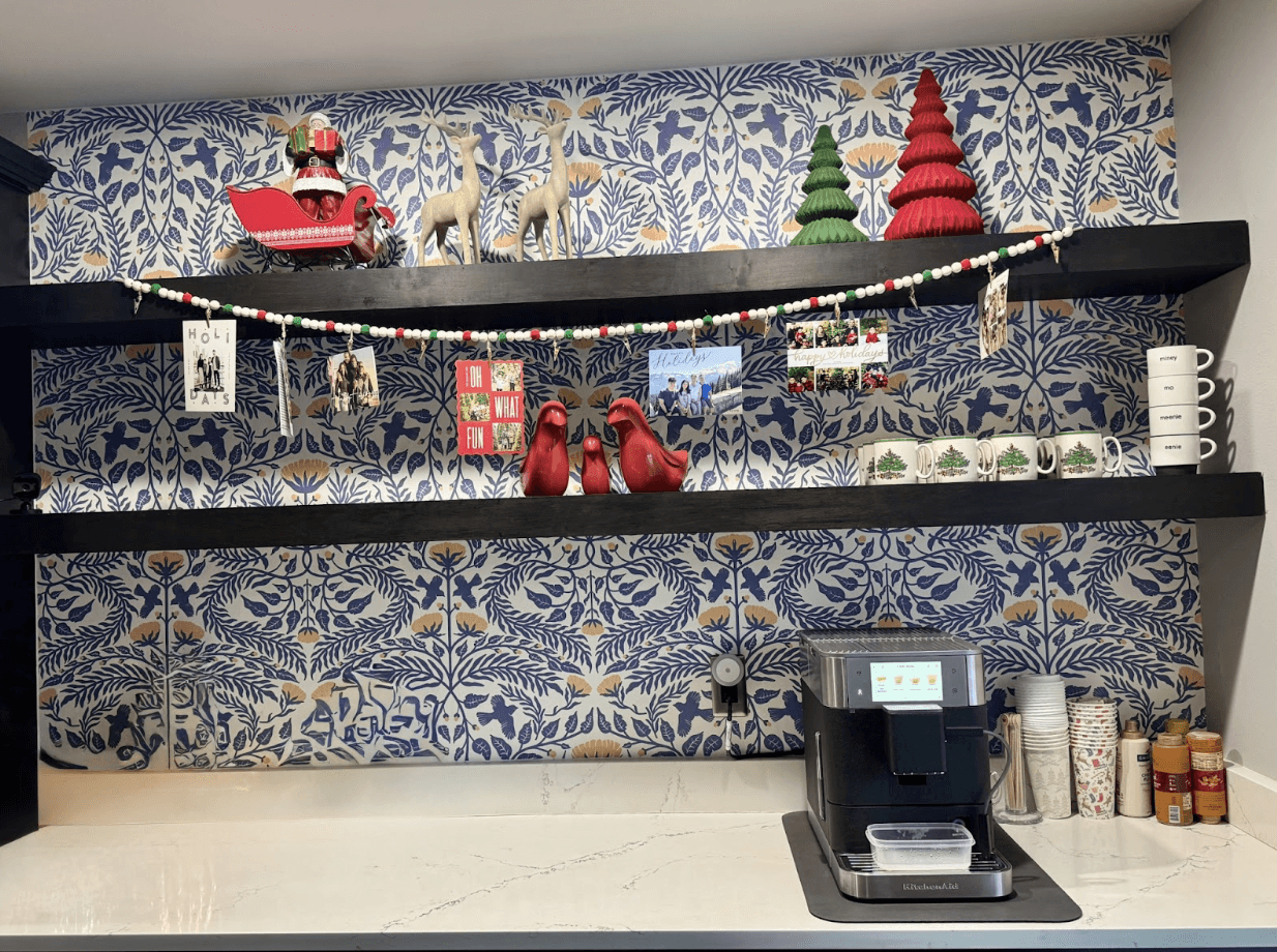 Custom black floating shelves installed over patterned designer wallpaper in a kitchen coffee nook