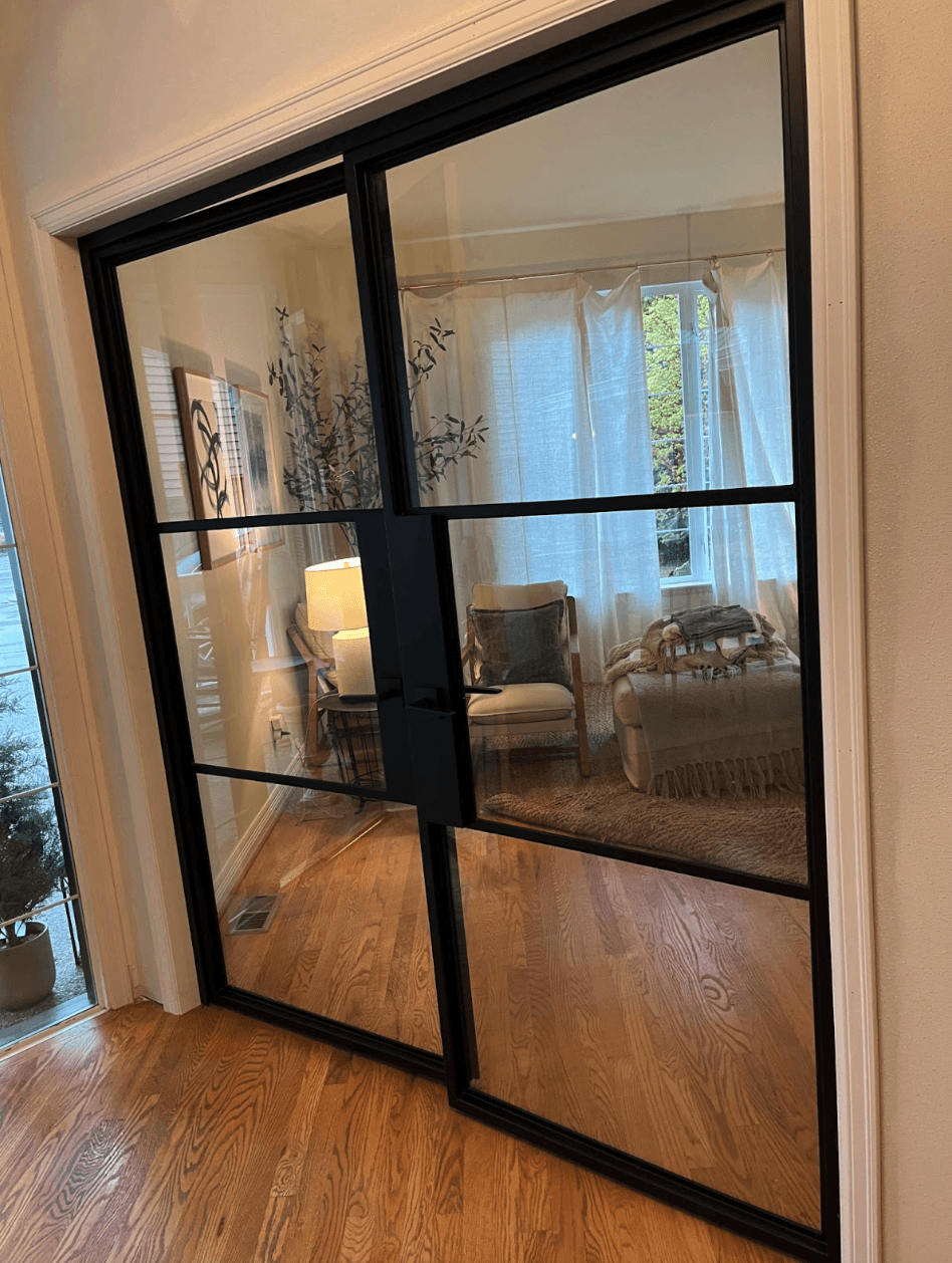 Steel-look glass partition doors installed in a remodeled living space with hardwood floors