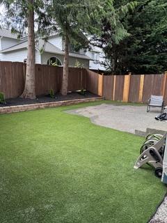 Landscaped backyard with fresh lawn, gravel border and a repaired cedar privacy fence