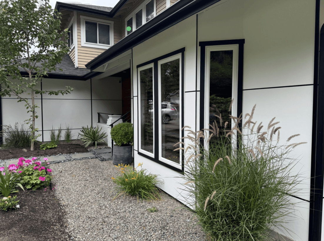 Home exterior with new siding, black-trimmed windows and a low-maintenance planted front yard